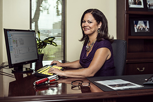 A woman sitting at a desk looking at the camera and smiling