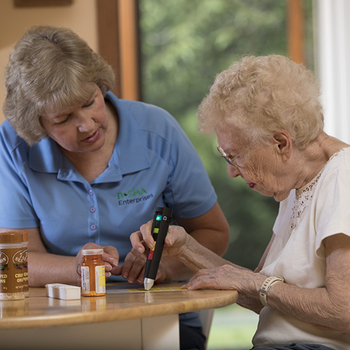 An elderly woman using a pen friend device.