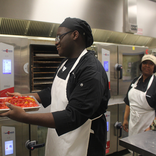 Student preparing tray of food with supervision