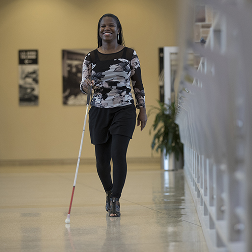 Woman walking down office corridor with cane