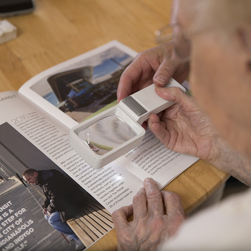 An elderly woman using a magnifier to read