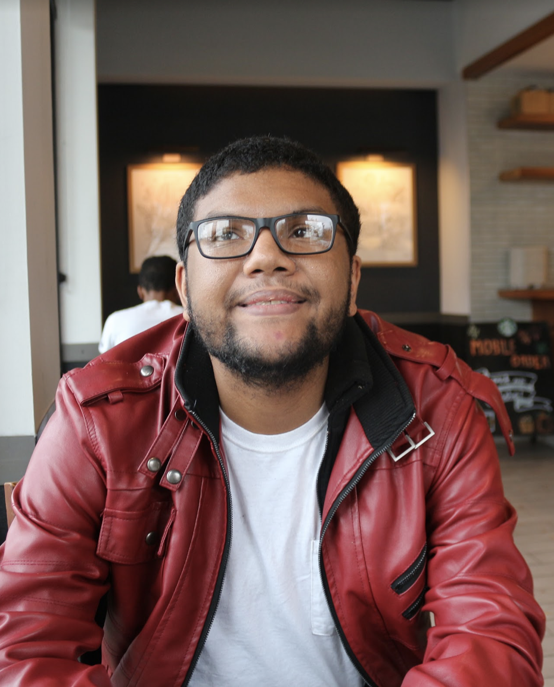 Man at a restaurant wearing glasses smiling 