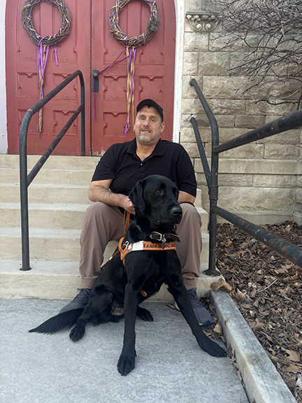Craig, a former client, posing with his new guide dog outside of church