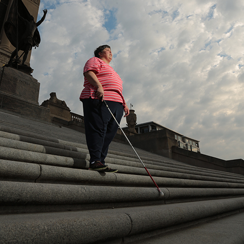 Woman with cane on steps of monument in Indy