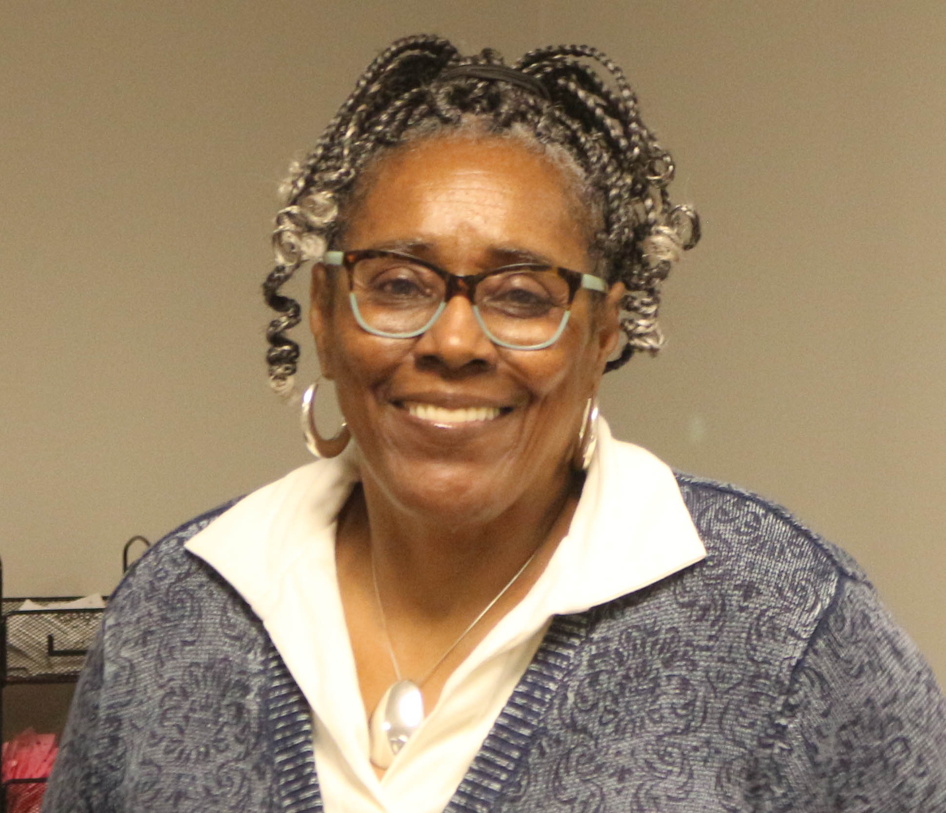 An African American woman with braided hair smiling at the camera