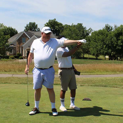 A man who is blind receives guidance on where he should hit his golf ball.