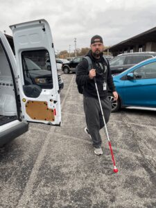 Joel Taulbee walking in parking lot with white cane.