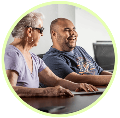 Man and woman sitting at table reading braille together.