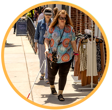 Two women walking on sidewalk outside of shops.