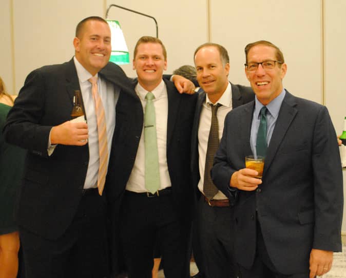 Group of men embracing smiling at camera.