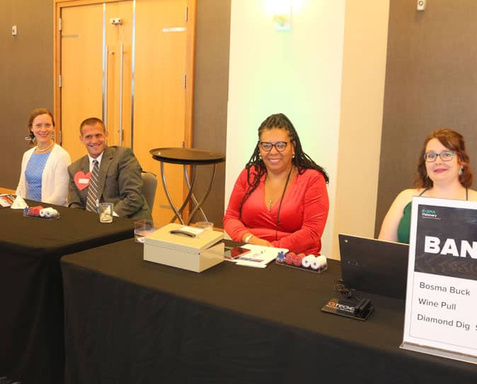 Group of people sitting at check-in table smiling at camera
