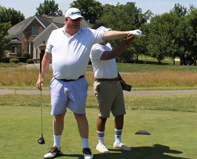 A man who is blind receives guidance on where he should hit his golf ball.