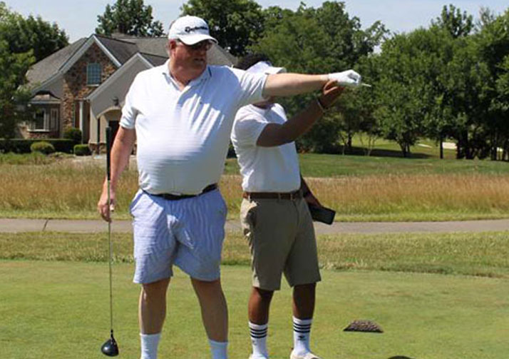 A man who is blind receives guidance on where he should hit his golf ball.