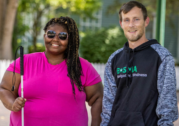 Aisha and Bosma employee standing on sidewalk smiling at camera.