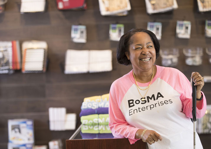 Woman standing in gift shop with white cane smiling.