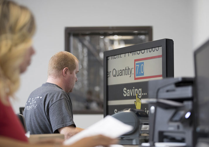 Man sitting at a computer in front of large monitor working.