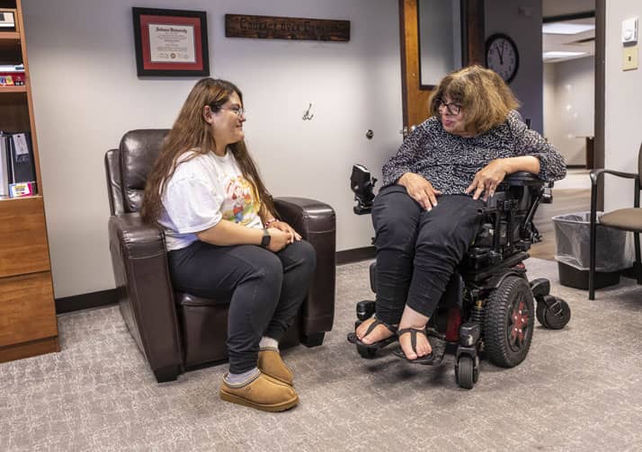 Woman in chair talking with woman in wheelchair in an office.