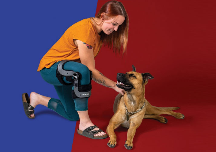 Women kneeling down petting dog while wearing Thuasne knee brace
