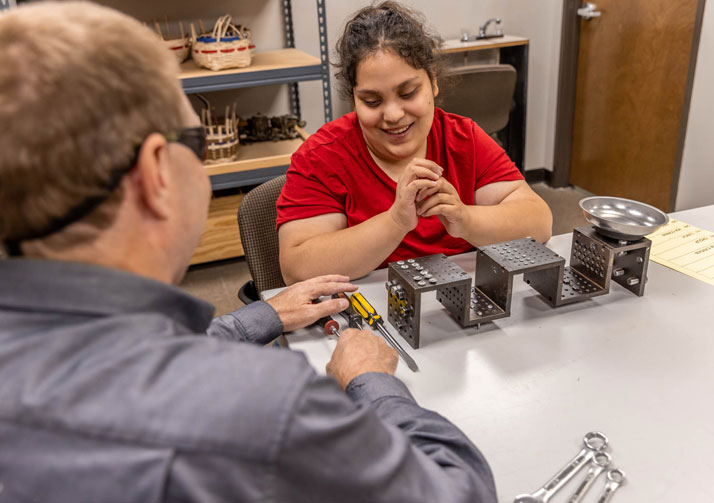Bosma instructor showing young woman how to manipulate tools.