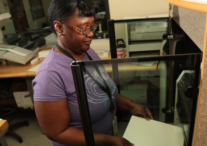 Woman loading papers into a machine.