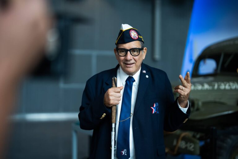 Terry Ferro wearing glasses in uniform standing in front of old Army vehicle.